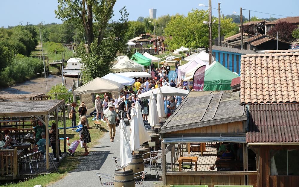 Le marché des producteurs au port de Saint-Vivien : chapiteaux, étals et visiteurs le long des cabanes ostréicoles